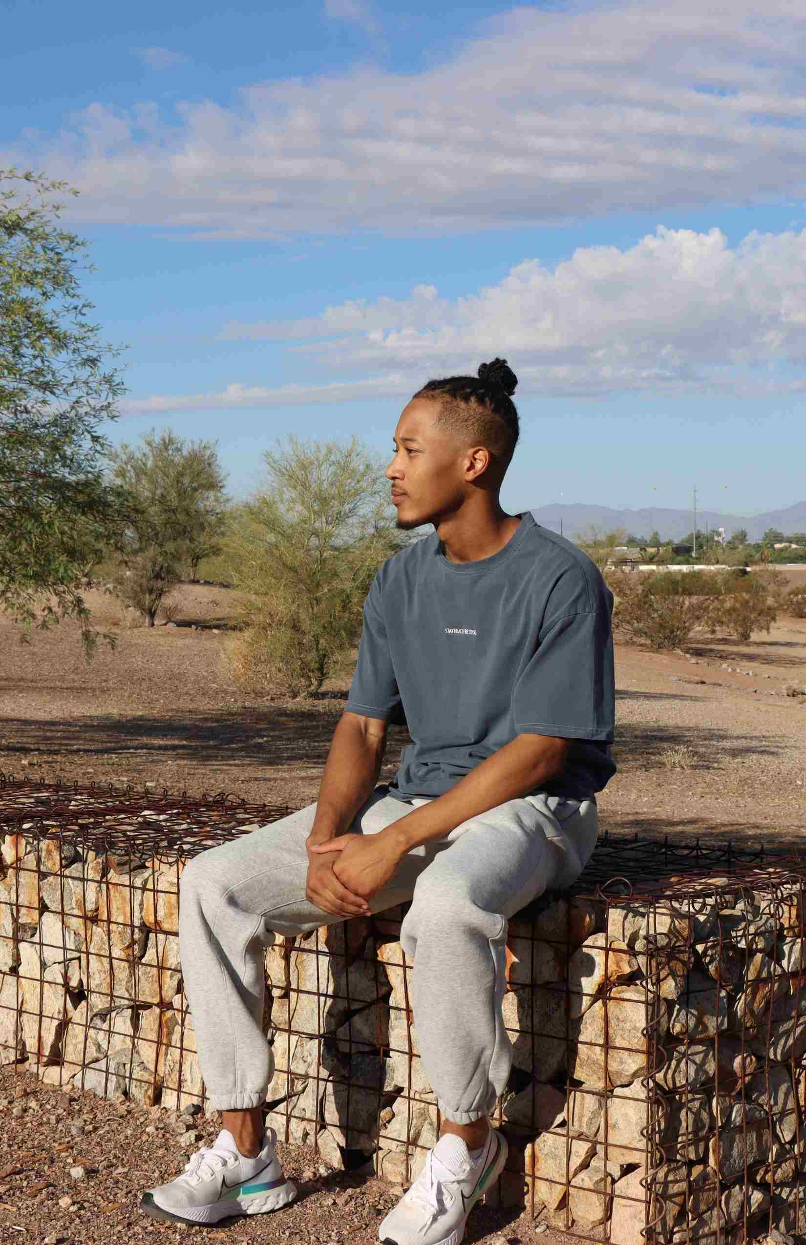 male sitting down wearing a faded blue oversized t-shirt with light gray oversized sweatpants