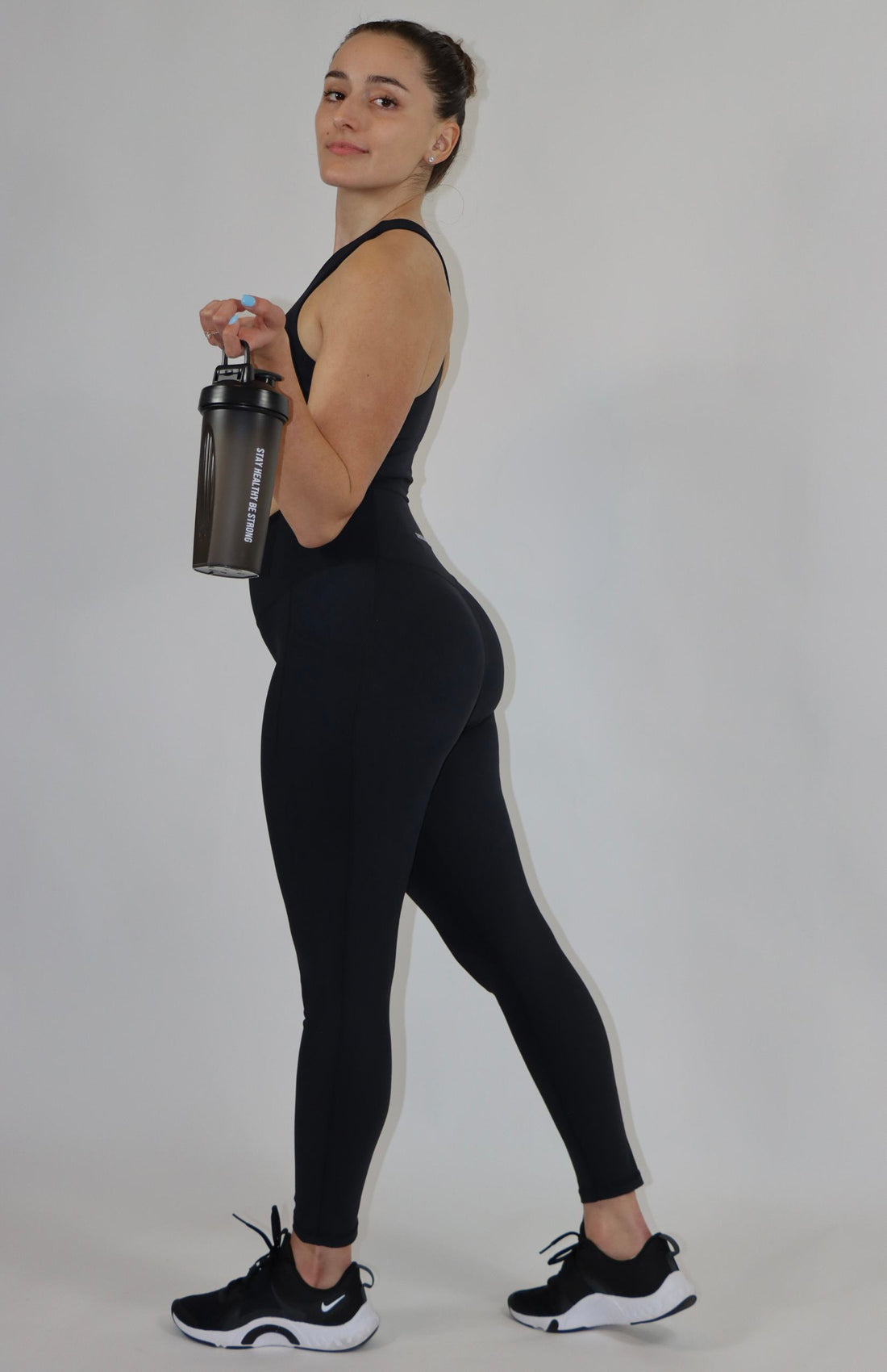 Black shaker bottle with black high waisted pocket leggings and black high-neck sports bra