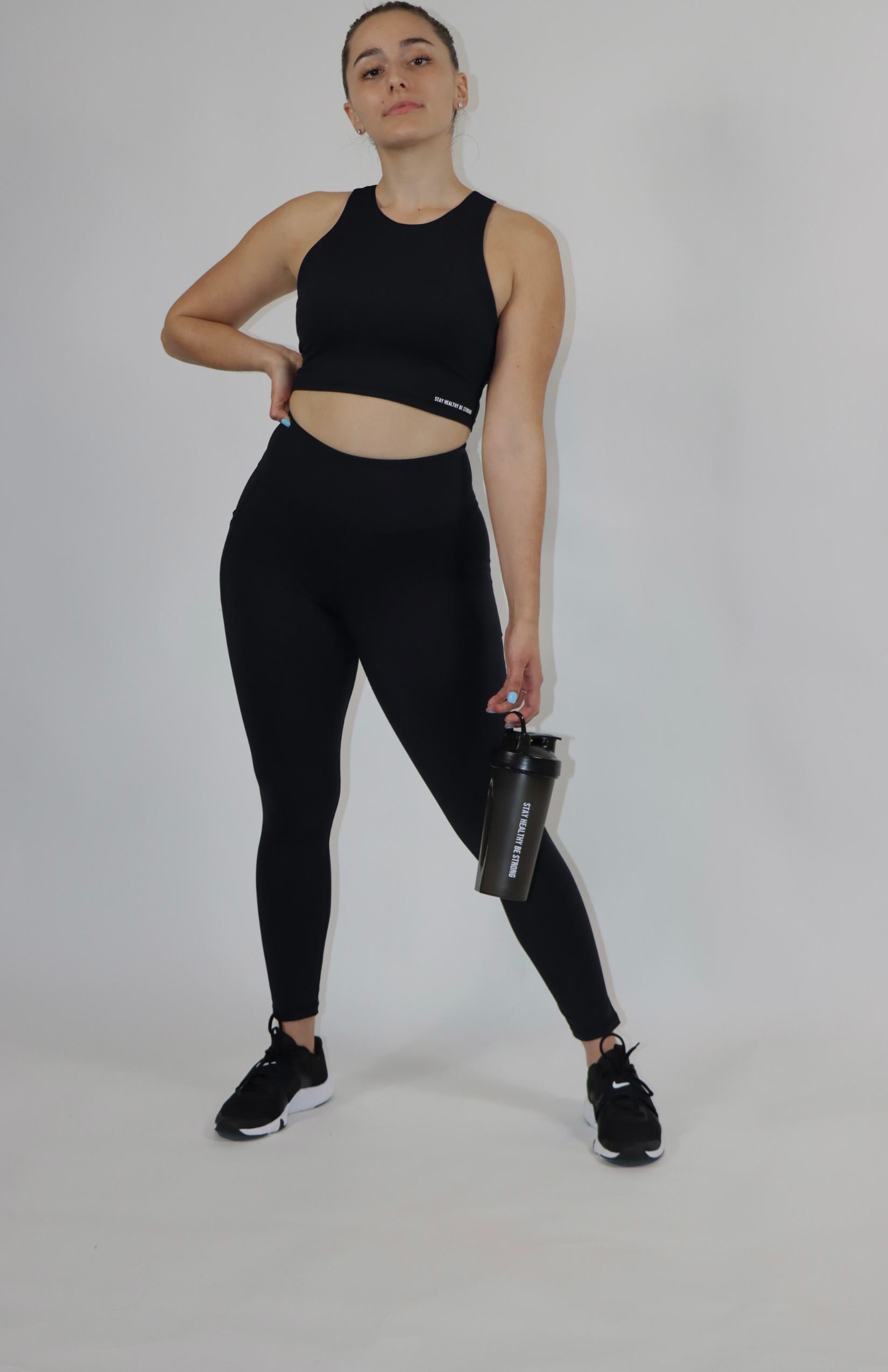 Black shaker bottle with black high waisted pocket leggings and black high-neck sports bra